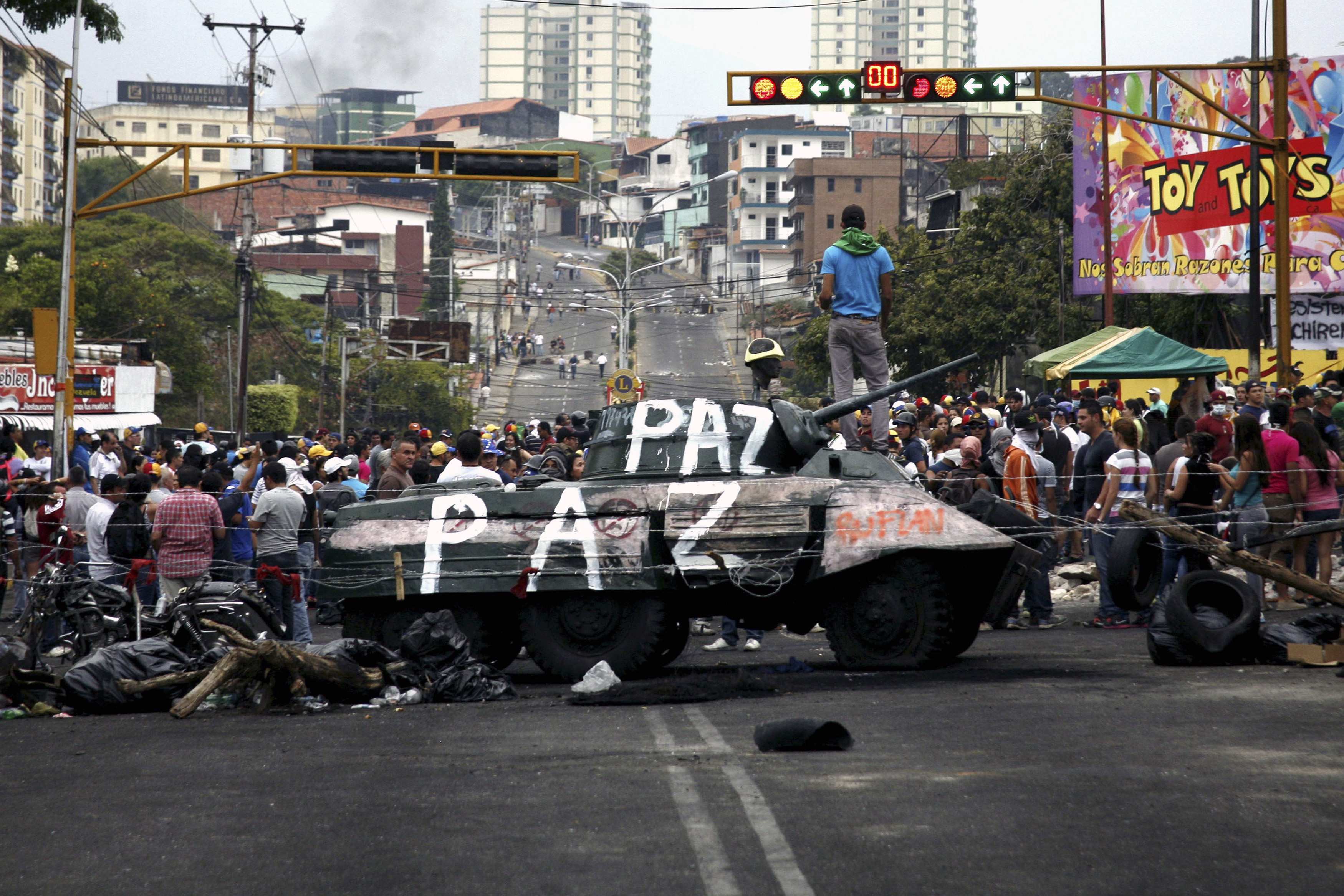 Opposition supporters stand over a monument of a tank which they dragged into the middle of the street during a protest against Nicolas Maduro’s government San Cristobal
