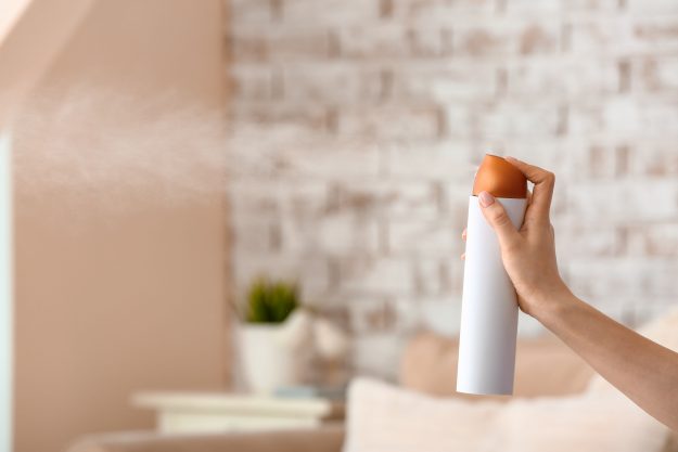 Woman spraying air freshener in room